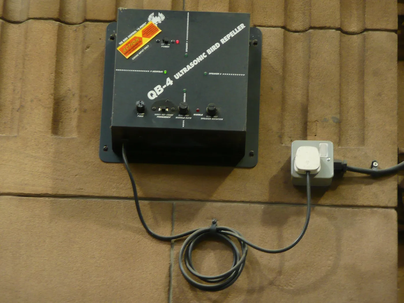 An ultrasonic bird repeller device mounted outdoors. These devices emit sounds birds cannot hear.